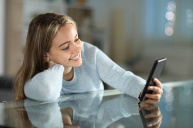 Mutlu genç gecenin bir yarısı evdeki oturma odasındaki masada akıllı telefon kullanıyor.