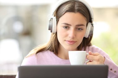 Kafede dizüstü bilgisayardan medyayı izleyen bilinçli bir kadının portresi.