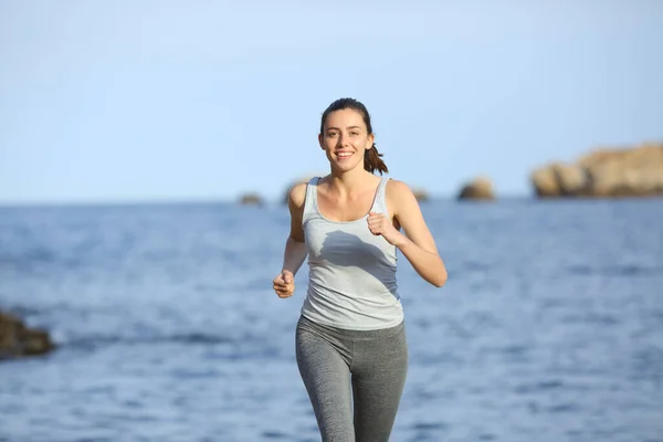 海岸を走る幸せな女性のフロントビューの肖像画 — ストック写真