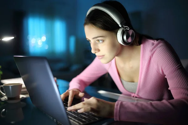 Συγκεντρωμένη Γυναίκα Που Φοράει Ασύρματα Ακουστικά Χρησιμοποιώντας Φορητό Υπολογιστή Βράδυ — Φωτογραφία Αρχείου