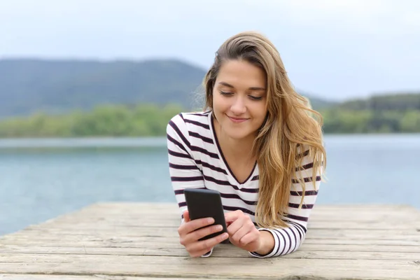 Vooraanzicht Van Een Vrolijke Vrouw Met Smartphone Liggend Een Meerpier — Stockfoto