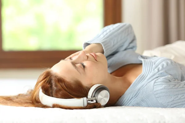 Жінка Розслабляється Ліжку Слухає Музику Бездротовими Навушниками Вдома — стокове фото
