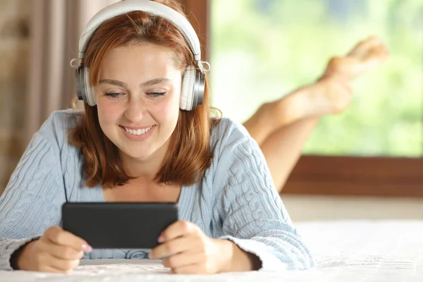 Widok Przodu Szczęśliwej Kobiety Noszącej Słuchawki Oglądającej Filmy Smartfonie Leżącym — Zdjęcie stockowe