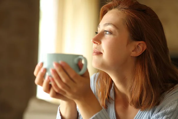 Zadowolona Kobieta Kontemplująca Przez Okno Pijąca Kawę Domu — Zdjęcie stockowe