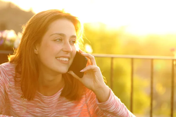日落时在阳台上用手机聊天的快乐女人 — 图库照片