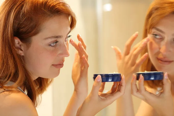 Woman Applying Moisturizer Cream Eye Bags Looking Mirror Bathroom Home — Zdjęcie stockowe