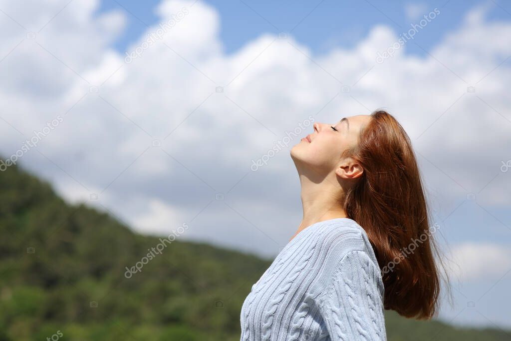 Profile of a woman breathing fresh air in the mountain with a cloudy sky
