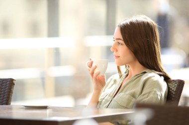 Barda kahve içen rahat bir kadının portresi.