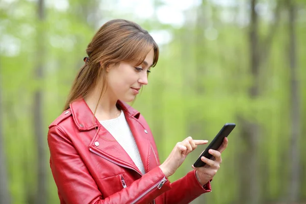 Perfil Una Mujer Seria Chequeo Rojo Del Teléfono Inteligente Bosque — Foto de Stock