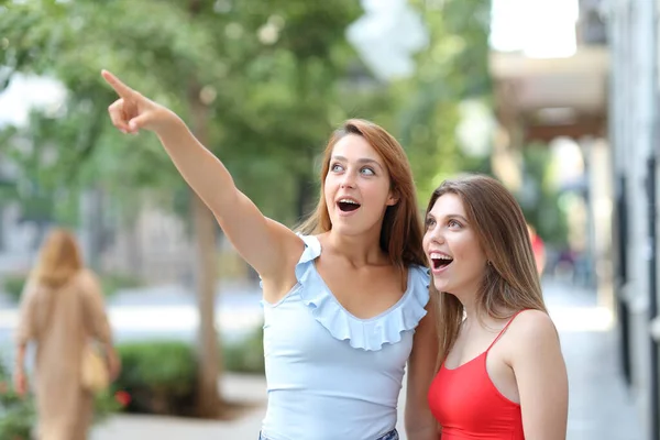 两个惊讶的女人指着街上的地标 — 图库照片