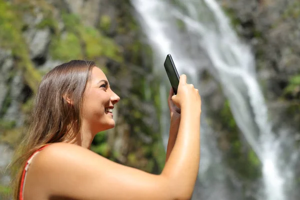 Profil Szczęśliwej Kobiety Robiącej Zdjęcia Smartfonem Wodospadzie — Zdjęcie stockowe
