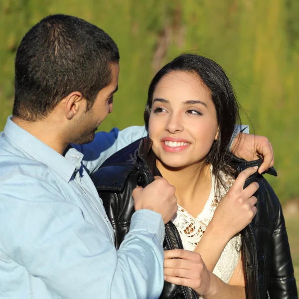 Glückliches arabisches Paar flirtet, während Mann sie in einem Park mit seiner Jacke bedeckt — Stockfoto