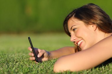 çimenlerin üzerinde bir akıllı telefon kullanan bir kız profili