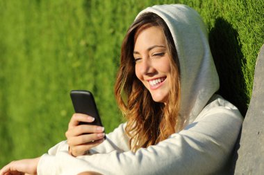 parkta bir akıllı telefon kullanan modern genç kız