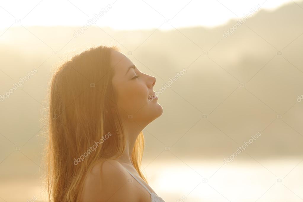 Woman breathing deep fresh air in the morning sunrise