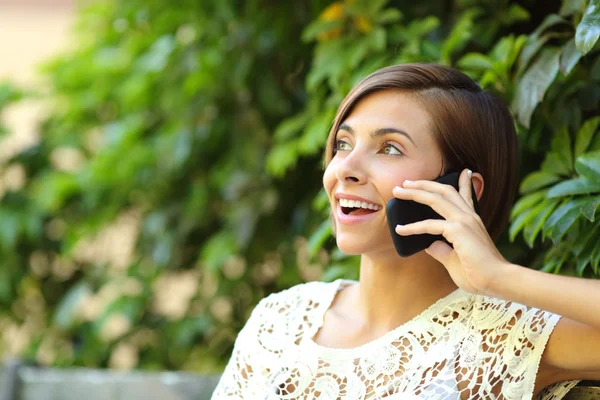 Случайная счастливая женщина по телефону в парке — стоковое фото