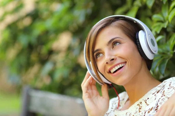 Ragazza che ascolta la musica con le cuffie in un parco — Foto Stock