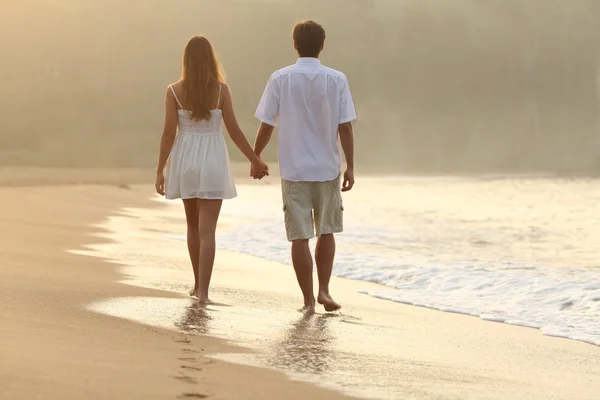 Paar wandel- en houden handen op het zand van het strand — Stockfoto