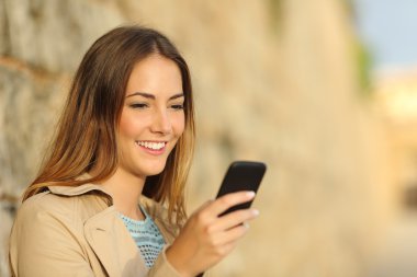 Eski bir kasabada bir akıllı telefon kullanan mutlu kadın