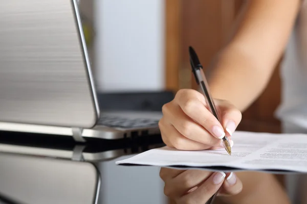 Mujer mano escribiendo un contrato con un ordenador portátil al lado — Foto de Stock