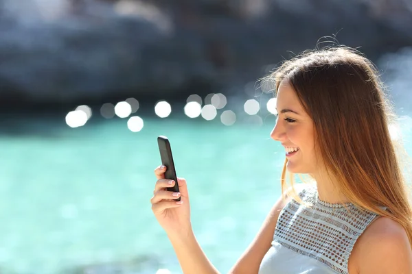 Mulher usando um telefone inteligente em uma praia tropical em férias — Fotografia de Stock