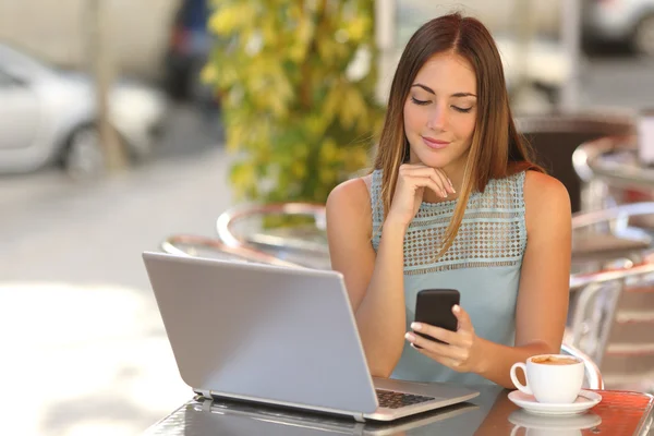 Самозайнята жінка працює зі своїм телефоном і ноутбуком в ресторані — стокове фото