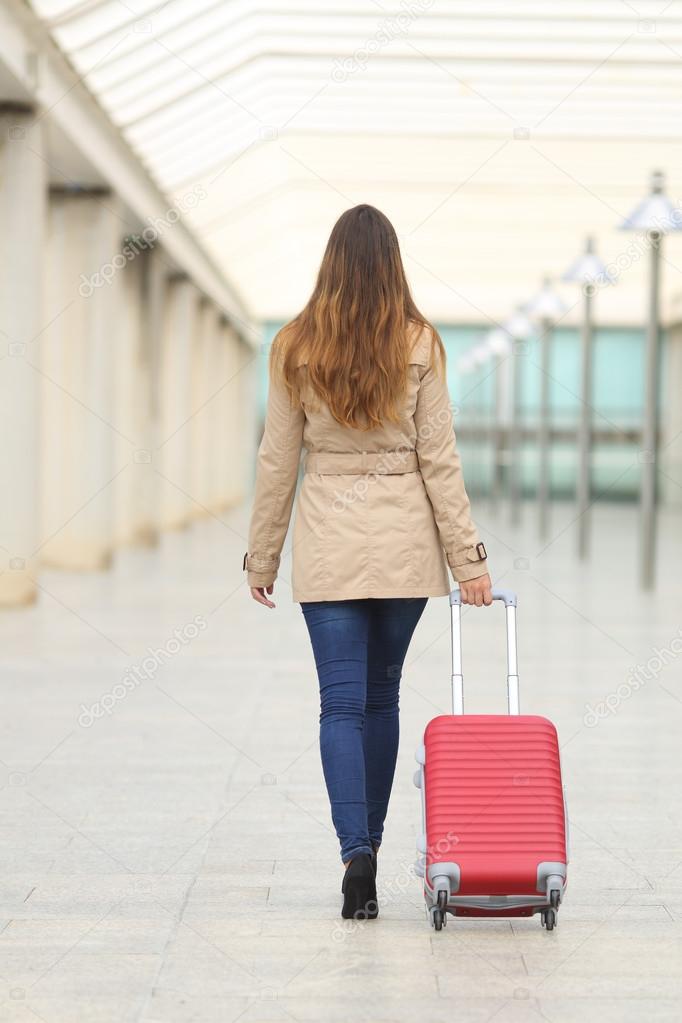 Tourist woman walking carrying a suit case in an airport