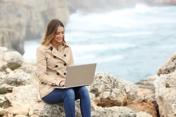 Vacker kvinna beter sin laptop i vinter på kusten — Stockfoto