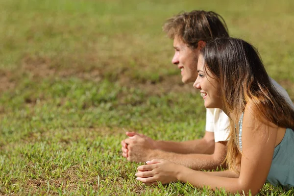 Pareja acostada en la hierba y mirando hacia otro lado — Foto de Stock