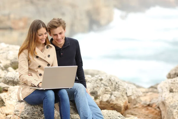 Pareja compartiendo un portátil en la playa en vacaciones — Foto de Stock