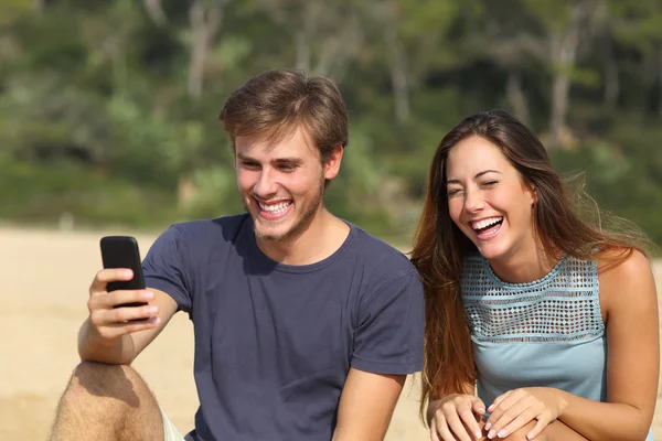 Engraçado homem e mulher rindo assistindo o telefone inteligente — Fotografia de Stock