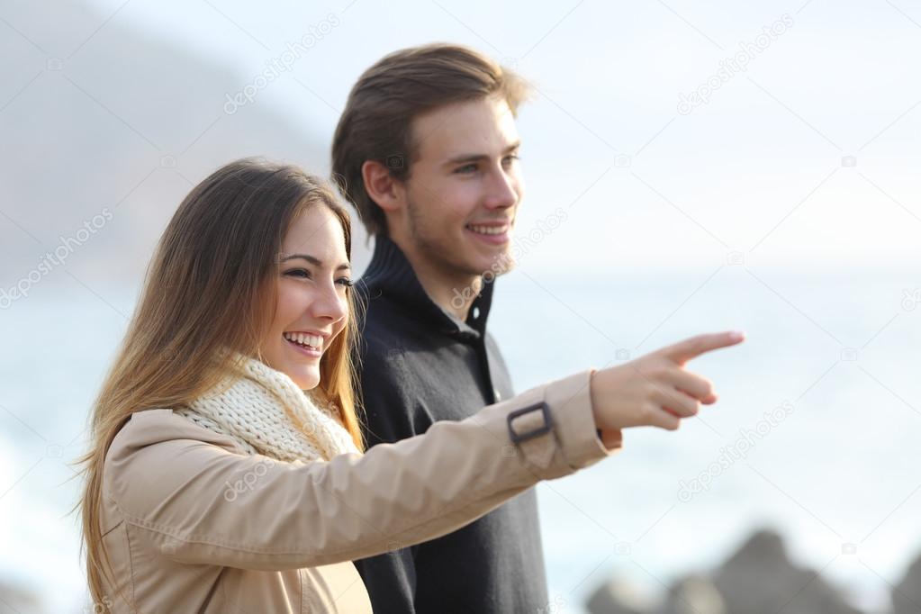 Couple looking forward on the beach and pointing