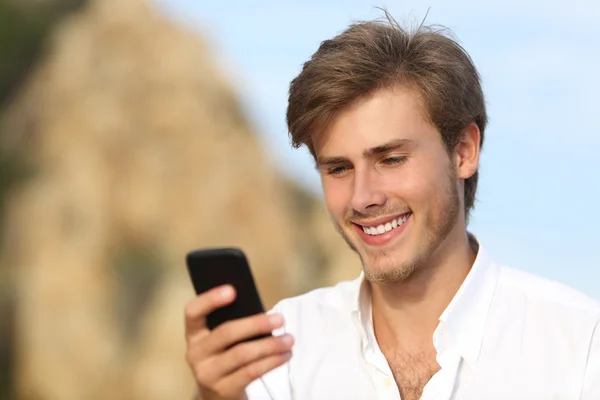 Knappe jongeman met behulp van een mobiele telefoon buiten — Stockfoto