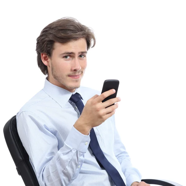 Jovem empresário sentado em uma cadeira usando um telefone inteligente — Fotografia de Stock