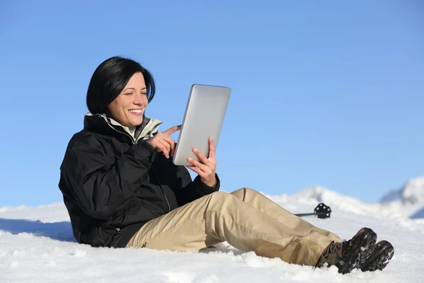 Mujer excursionista feliz navegando una tableta en la nieve —  Fotos de Stock