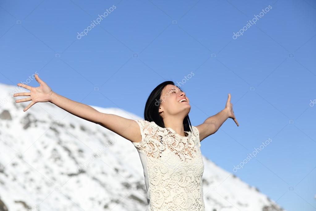 Happy woman breathing deep raising arms in winter