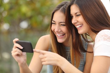 Gülüyor ve bir akıllı telefon medya paylaşımı iki komik kadın arkadaş 