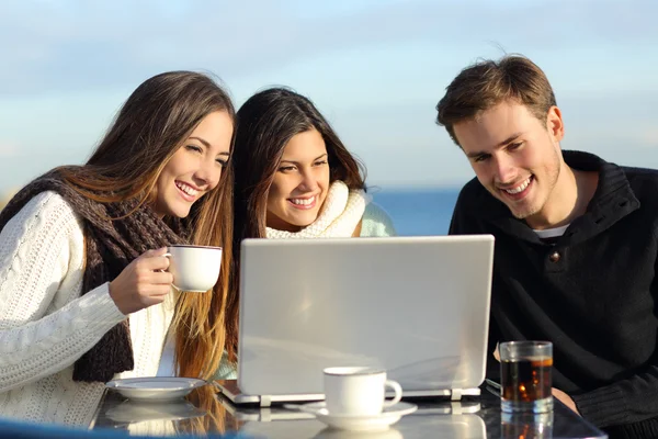 Groep vrienden kijken naar een laptop in een restaurant — Stockfoto