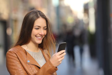 Sokakta bir akıllı telefon kullanan mutlu kadın