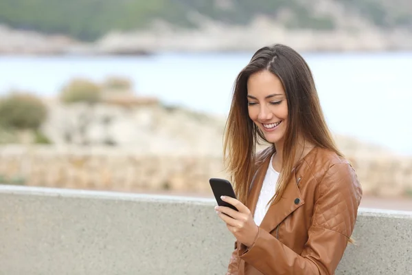 Szczęśliwa kobieta przy pomocy pewien silny telefon na plaży z kopią — Zdjęcie stockowe