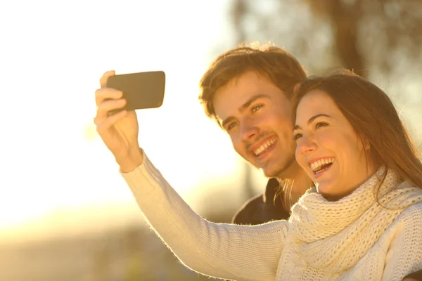 Pareja tomando foto selfie con un teléfono inteligente al atardecer — Foto de Stock