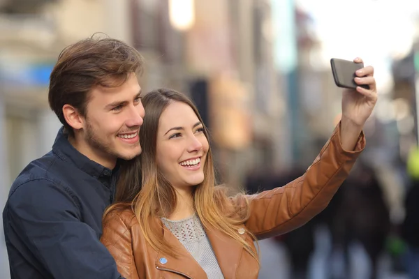 Couple taking selfie photo with a smart phone in the street — Stock Photo, Image