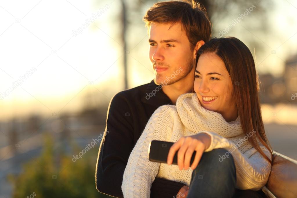 Couple relaxing and hugging looking at sunset