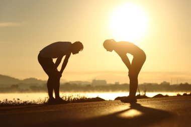 Bitkin ve yorgun fitness çift siluetleri gün batımında