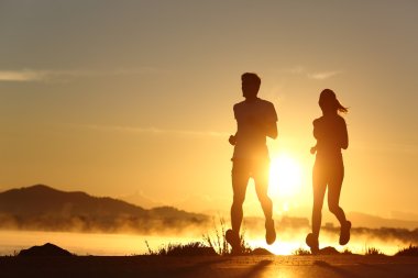 Silhouette of a couple running at sunset clipart