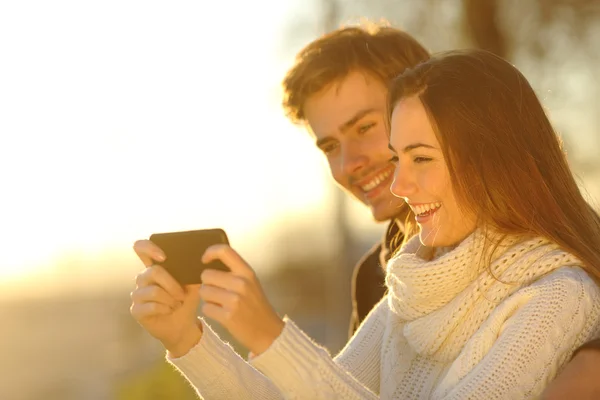 Casal assistindo vídeos de mídia em um telefone inteligente — Fotografia de Stock