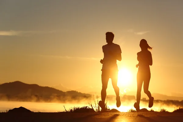 Silueta pár běží při západu slunce — Stock fotografie