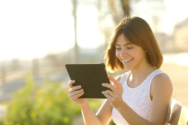 Gelukkige vrouw met behulp van een tablet buitenshuis — Stockfoto