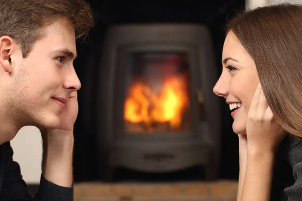 Paar kijken elkaar op de voorgrond een open haard — Stockfoto