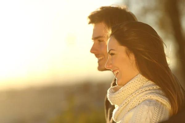 Casal feliz olhando para o pôr do sol no inverno — Fotografia de Stock